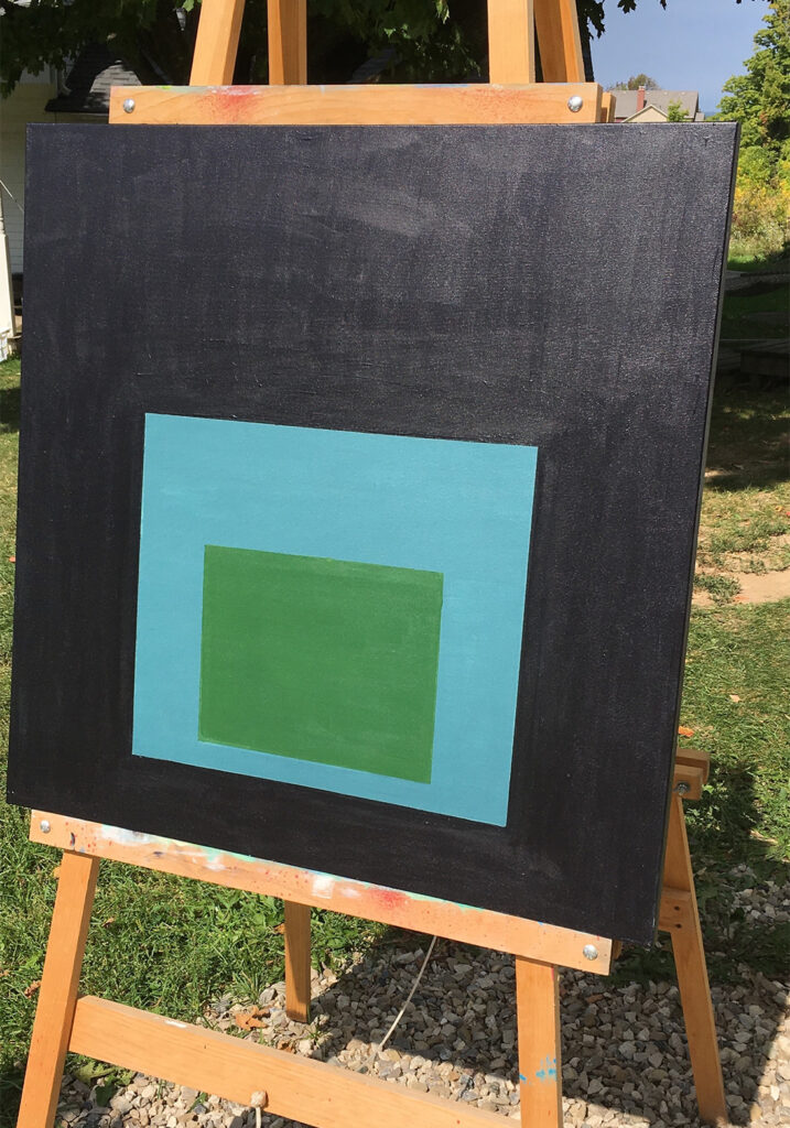 painting on an easel outdoors on a sunny day